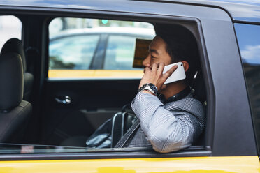 Geschäftsmann, der im Taxi sitzend mit seinem Smartphone telefoniert - CAVF47666