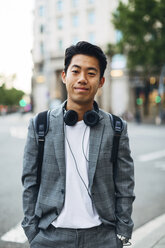 Portrait of confident businessman with hands in pockets standing on footpath in city - CAVF47669