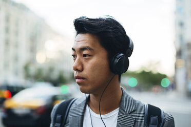 Businessman looking away while listening music in city - CAVF47670