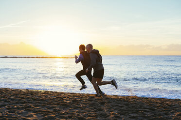 Vater und Sohn joggen in voller Länge am Strand gegen den Himmel - CAVF47752