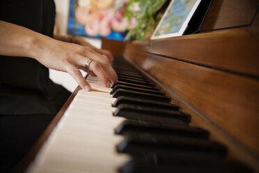 Cropped image of woman's hands playing piano at home - CAVF47778