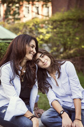 Smiling mother and daughter resting at park - CAVF47834