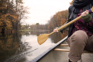 Midsection of woman rowing boat on lake at forest during winter - CAVF47874