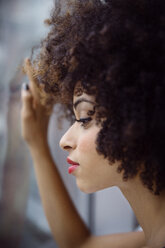 Close-up of thoughtful woman with curly hair looking through window - CAVF47916