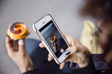 Ausgeschnittenes Bild einer Frau, die mit ihrem Smartphone ein Törtchen fotografiert - CAVF47928