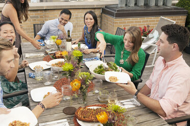 Hoher Blickwinkel von Freunden beim Essen am Tisch auf der Terrasse eines Gebäudes - CAVF47957