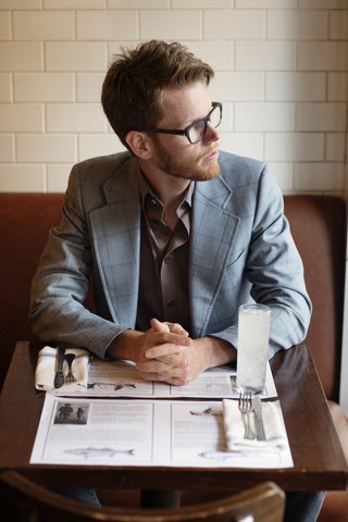 Nachdenklicher Mann, der am Tisch im Restaurant sitzt und wegschaut, lizenzfreies Stockfoto