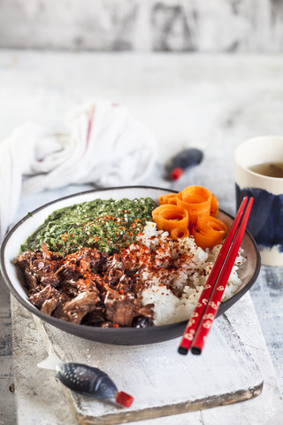 Vegane Teriyaki-Bowl mit gezupftem Teriyaki-Rindfleisch aus Jackfruit, Spinat, Reis und Karotten, lizenzfreies Stockfoto