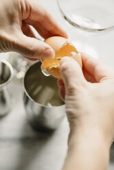 Cropped image of woman breaking egg in drinking glass - CAVF48094