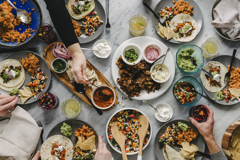 Abgeschnittene Hände von Freunden beim Essen am Tisch während eines geselligen Beisammenseins, lizenzfreies Stockfoto