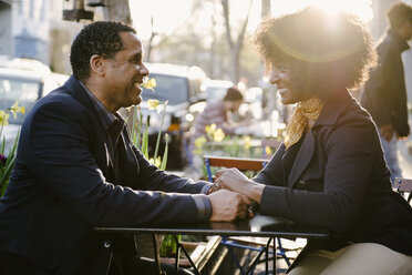 Glückliches Paar, das sich gegenseitig ansieht, während es in einem Straßencafé in der Stadt sitzt - CAVF48132