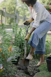 Woman shoveling soil in garden - CAVF48144