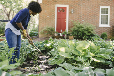Woman using gardening fork while working in yard - CAVF48156