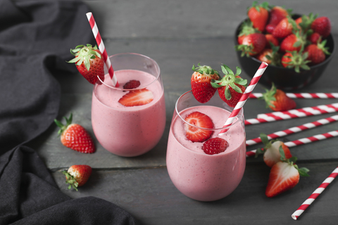 Gläser mit Erdbeer-Smoothie und Erdbeeren auf dunklem Holz, lizenzfreies Stockfoto