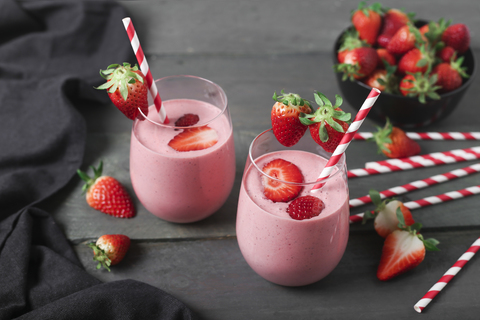 Glasses of strawberry smoothie and strawberries on dark wood stock photo