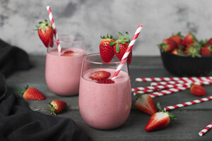 Gläser mit Erdbeer-Smoothie und Erdbeeren auf dunklem Holz - RTBF01203