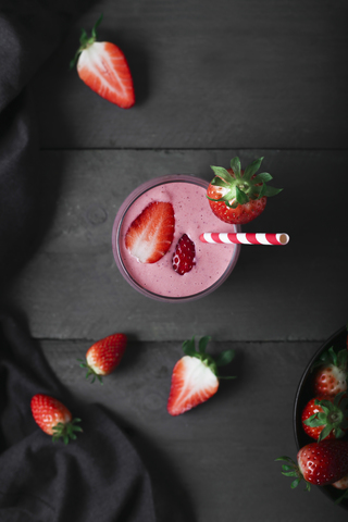 Glasses of strawberry smoothie and strawberries on dark wood stock photo
