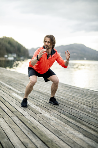 Athlete exercising on wooden deck at the lakeshore stock photo