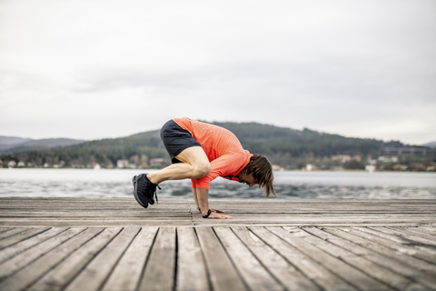 Athlete exercising on wooden deck at the lakeshore stock photo