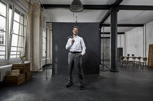 Porträt eines reifen Geschäftsmannes vor einem schwarzen Hintergrund in einem Loft - PDF01562