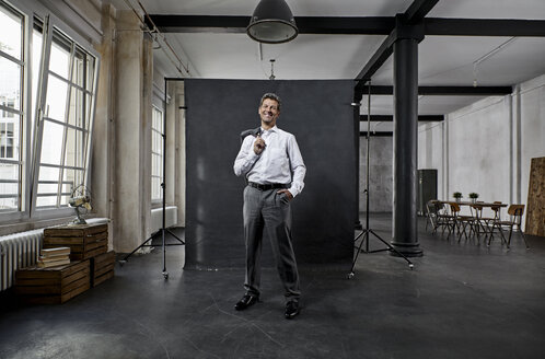 Portrait of mature businessman in front of black backdrop in loft - PDF01562