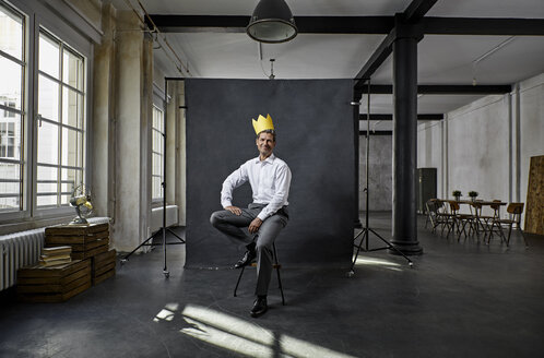 Portrait of mature businessman with crown in front of black backdrop in loft - PDF01565