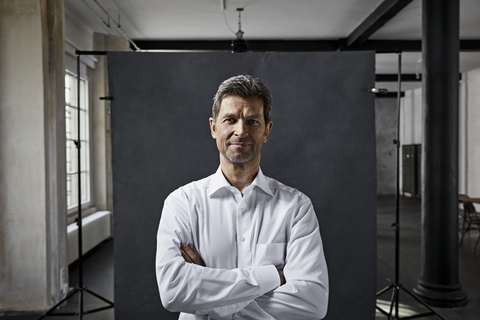Portrait of mature businessman in front of black backdrop in loft stock photo