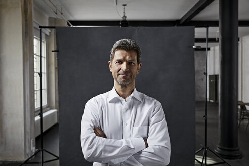 Porträt eines reifen Geschäftsmannes vor einem schwarzen Hintergrund in einem Loft - PDF01566