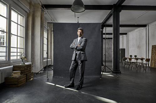 Portrait of mature businessman in front of black backdrop in loft - PDF01567