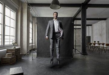 Mature businessman floating in front of black backdrop in loft - PDF01573