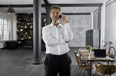 Portrait of mature business man using smartphone in loft office - PDF01588