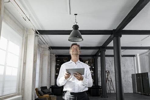 Mature man using digital tablet in loft flat - PDF01590