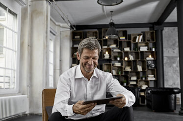 Smiling mature man using digital tablet in loft - PDF01600