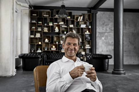Porträt eines reifen Mannes, der in einem Loft eine Tasse Kaffee genießt, lizenzfreies Stockfoto