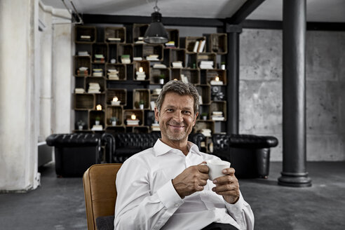 Porträt eines reifen Mannes, der in einem Loft eine Tasse Kaffee genießt - PDF01604