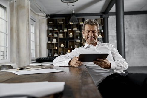 Smiling mature man using digital tablet in loft office - PDF01612