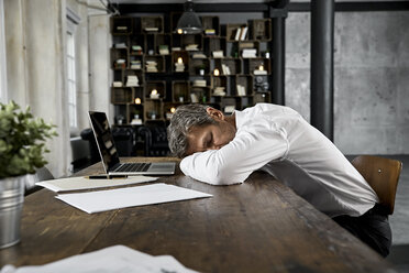 Mature businessman sleeping on desk in loft - PDF01614