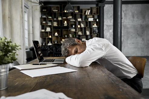 Älterer Geschäftsmann schläft auf dem Schreibtisch im Loft - PDF01614