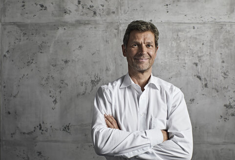 Portrait of smiling mature man in front of concrete wall - PDF01617