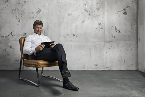 Mature man using digital tablet in front of concrete wall - PDF01619