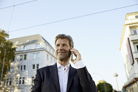 Älterer Geschäftsmann mit Smartphone in der Stadt, lizenzfreies Stockfoto