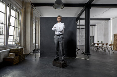 Portrait of mature businessman in front of black backdrop in loft - PDF01625