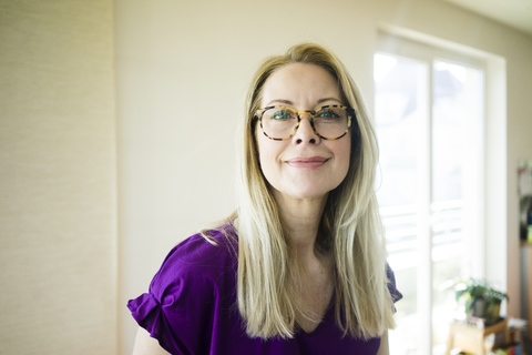 Porträt einer lächelnden blonden reifen Frau mit Brille, lizenzfreies Stockfoto