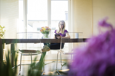 Geschäftsfrau sitzt am Besprechungstisch und benutzt ein Tablet, lizenzfreies Stockfoto