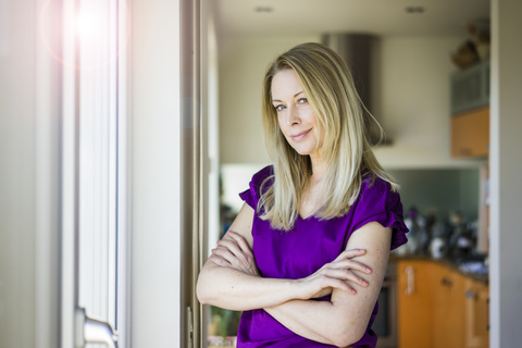 Portrait of smiling blond mature woman at home stock photo