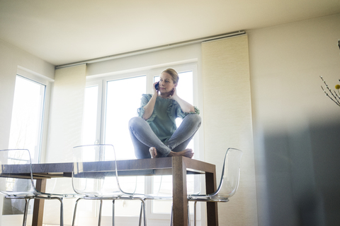 Businesswoman on the phone sitting barefoot on meeting table stock photo