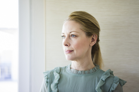 Portrait of blond mature woman looking out of window stock photo