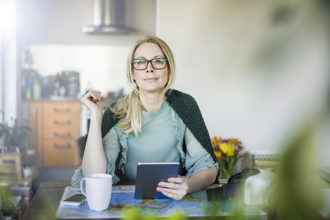 Portrait of blond businesswoman with tablet and world map stock photo