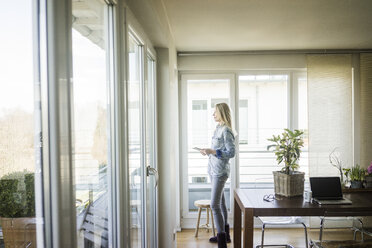 Frau mit Tablet und Blick aus dem Fenster - MOEF01069