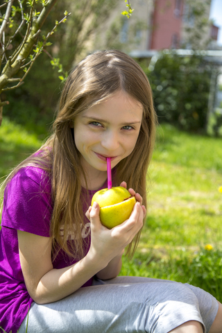 Porträt eines lächelnden Mädchens, das einen Erdbeer-Smoothie im Garten trinkt, lizenzfreies Stockfoto